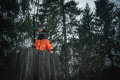 Myśliwy w terenie ubrany w kurtkę Seeland Trax Blaze oraz czapkę ostrzegawczą – zdjęcie prezentuje jaskrawy kolor Hi-Vis Orange, który zapewnia bezpieczeństwo i widoczność w gęstym lesie podczas polowań zbiorowych.