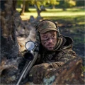 Widok z przodu na myśliwego w lesie noszącego czapkę Härkila Deer Stalker HWS. Ujęcie ukazuje, jak kamuflaż cyfrowy AXIS MSP skutecznie wtapia sylwetkę w naturalne otoczenie łowiska.