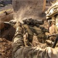 Taktyczna luneta biegowa Vortex AMG 1-10x24 FFP zamontowana na sportowym karabinie typu AR-15. Zdjęcie z boku w naturalnym, terenowym otoczeniu (wiosenny las/strzelnica), podkreślające kompaktową budowę LPVO idealną do strzelań dynamicznych.